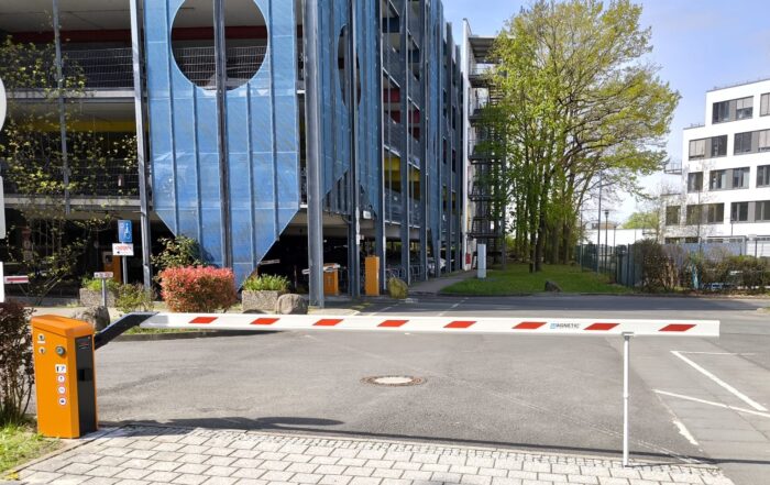 Geschlossene Schranke vor einem blau verspiegelten Bürogebäude