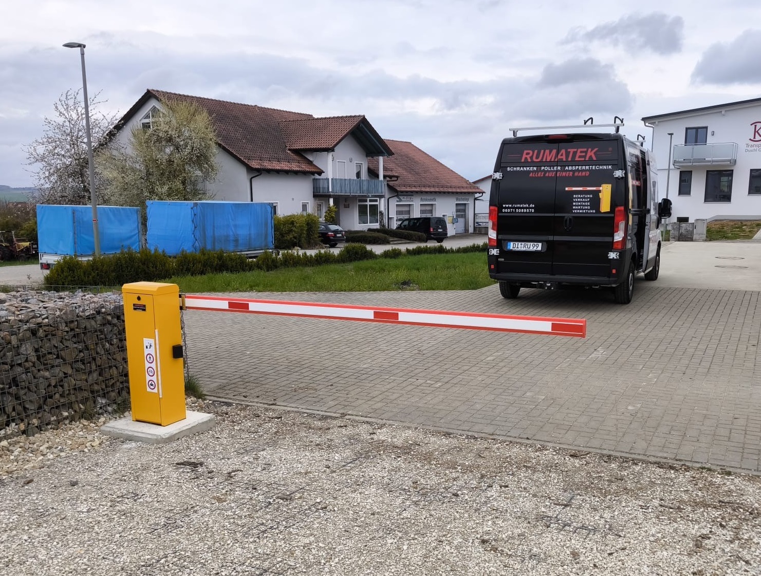 Automatische Schranke vor einem Kleintransporter mit Aufschrift