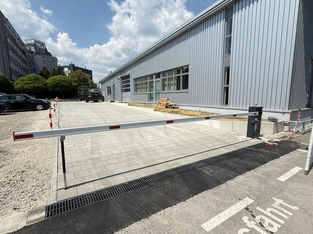 Schranke vor eine Industriehalle und einem Parkplatz