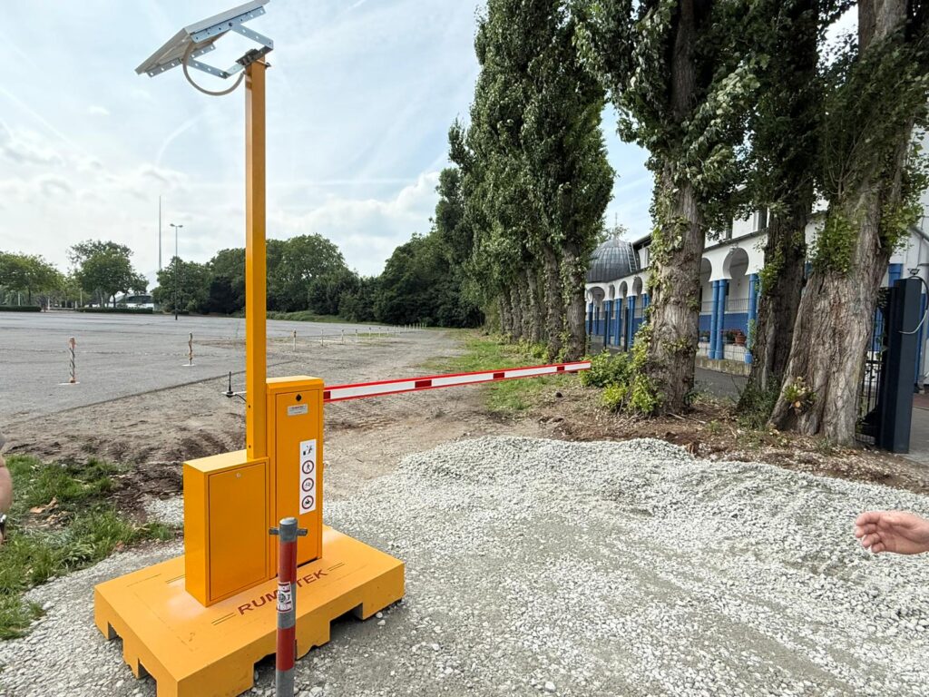 Gelbe Schranke auf mobiler Platte mit Solarpanel auf einem Kiesweg