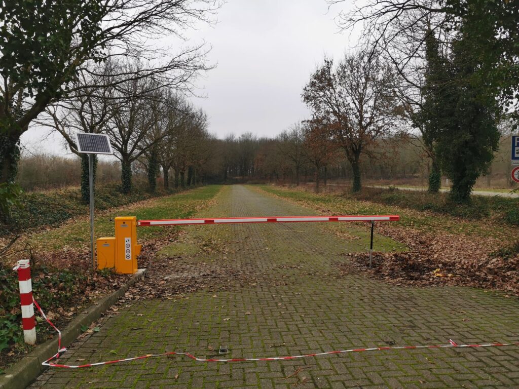 Gelbe Schranke mit Solarpaneelen vor einem Forstweg